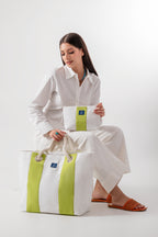 Woman holding a white and green bag with a visible brand logo on a white background